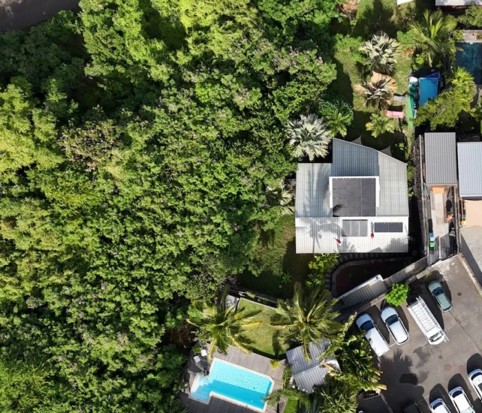 Installation de panneaux solaires en autoconsommation à La Réunion par Solar Service. Client content devant sa maison et sa piscine.