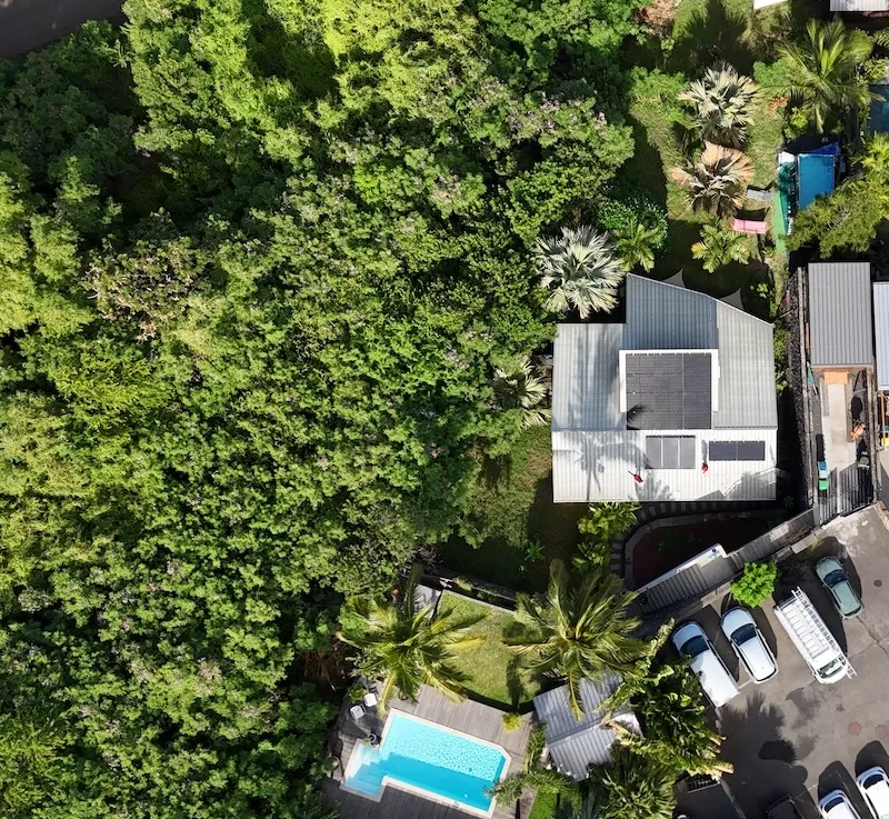 Installation de panneaux solaires en autoconsommation à La Réunion par Solar Service. Client content devant sa maison et sa piscine.