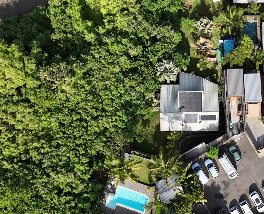 Installation de panneaux solaires en autoconsommation à La Réunion par Solar Service. Client content devant sa maison et sa piscine.