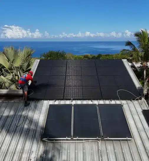 Technicien installant des panneaux photovoltaïques sur un toit face à l’océan à La Réunion