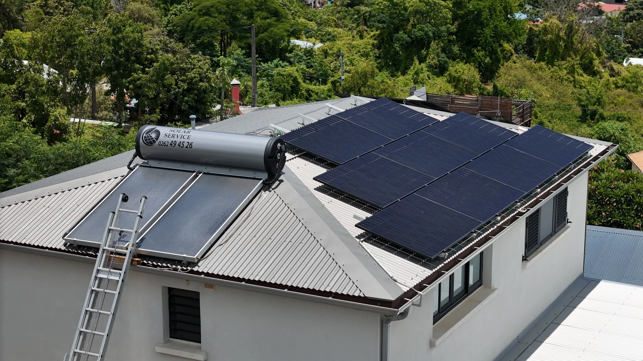Exemple de différence sur un toit à La Réunion entre un panneau solaire pour l'eau chaude et des panneaux photovoltaïques
