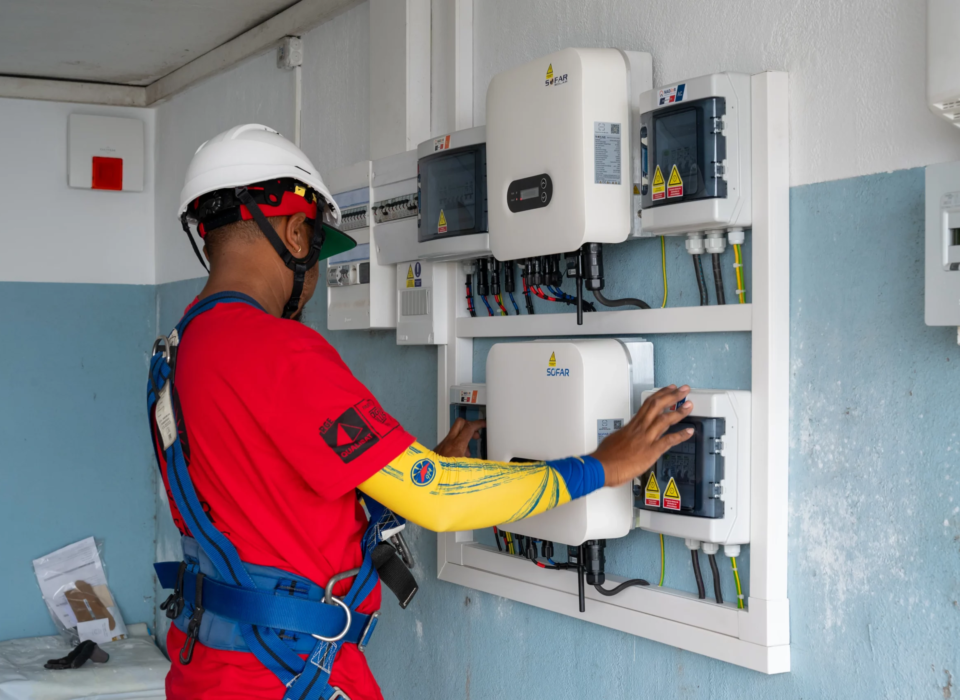 Technicien Solar Service installant des panneaux photovoltaïques met en place l'onduleur.