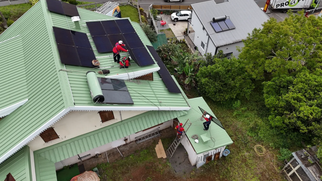 Techniciens Solar Service sécurisés posant des modules photovoltaïques sur un toit multi pan.