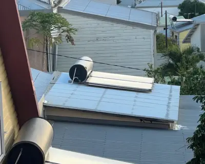 Plusieurs chauffe-eau solaires installés sur des toitures de cases réunionnaises avec vue sur l'océan