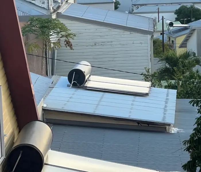 Plusieurs chauffe-eau solaires installés sur des toitures de cases réunionnaises avec vue sur l'océan