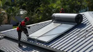 Techniciens Solar Service en tenue rouge installant un chauffe-eau solaire thermosiphon sur toiture à La Réunion
