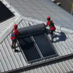 Vue aérienne d'un chauffe-eau solaire et de panneaux photovoltaïques installés sur la même toiture à La Réunion