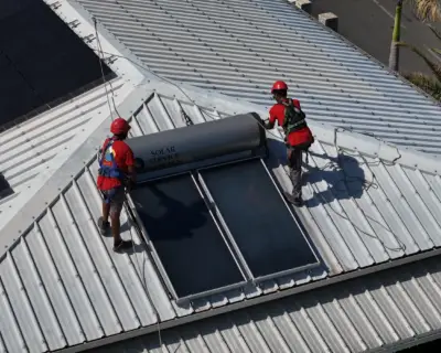 Vue aérienne d'un chauffe-eau solaire et de panneaux photovoltaïques installés sur la même toiture à La Réunion