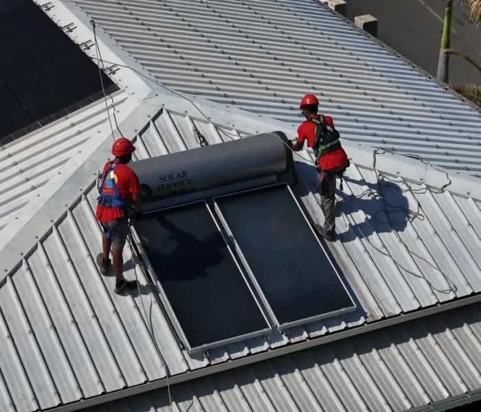 Vue aérienne d'un chauffe-eau solaire et de panneaux photovoltaïques installés sur la même toiture à La Réunion