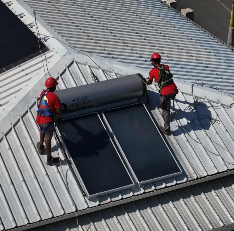 Vue aérienne d'un chauffe-eau solaire et de panneaux photovoltaïques installés sur la même toiture à La Réunion
