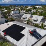 Techniciens Solar Service installant un chauffe-eau solaire et des panneaux photovoltaïques sur une toiture en bord de mer à La Réunion