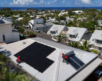 Techniciens Solar Service installant un chauffe-eau solaire et des panneaux photovoltaïques sur une toiture en bord de mer à La Réunion