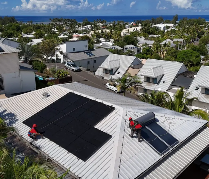 Techniciens Solar Service installant un chauffe-eau solaire et des panneaux photovoltaïques sur une toiture en bord de mer à La Réunion
