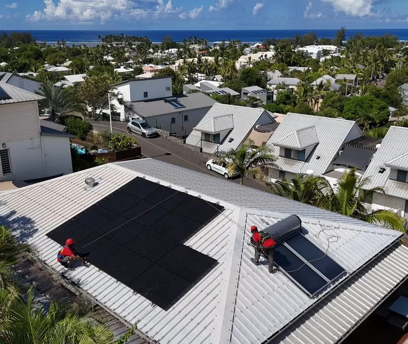 Techniciens Solar Service installant un chauffe-eau solaire et des panneaux photovoltaïques sur une toiture en bord de mer à La Réunion