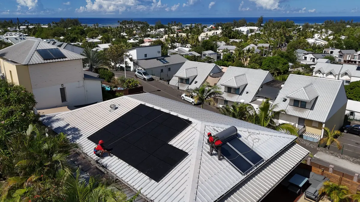 Techniciens Solar Service installant un chauffe-eau solaire et des panneaux photovoltaïques sur une toiture en bord de mer à La Réunion